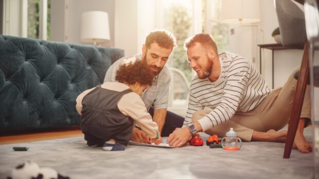 Cheerful gay couple nurturing a child