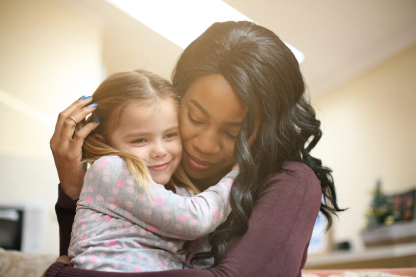 African American woman hugging her adopted daughter