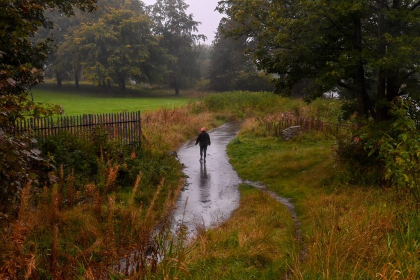 A person braves the wet conditions at Donside Village, Aberdeen.