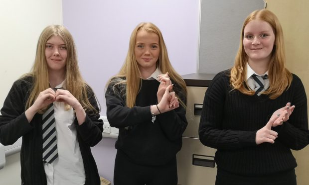 Three Dingwall Academy pupils demonstrate their BSL signing skills.