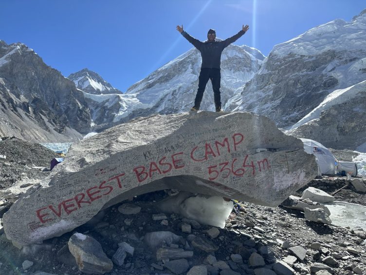Davie stands on a rock with the words "Everest base Camp 5364m"
