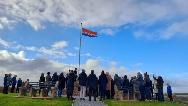 People standing look at the newly unveiled Banffshire flag in Cullen.