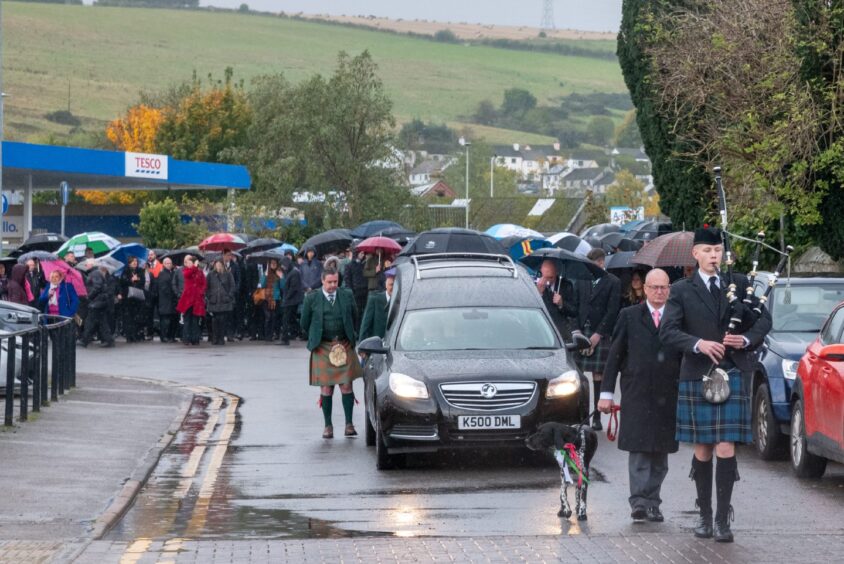 A bagpiper pipes the hearse at Kirsteen Maclennan's funeral.