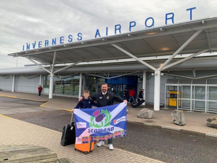 Alastair and his father Steven holding the Scottish flag outside Inverness Airport.