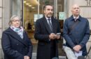 Solicitor Aamer Anwar (centre) gives a statement on behalf of the Scottish Covid Bereaved before a hearing at the Covid-19 pandemic inquiry at George House in Edinburgh. Image: PA