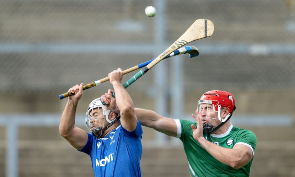 Scotland's Iain Robinson battles with Fionan MacKessy of Ireland in the shinty/hurling International at Pairc Esler, Newry