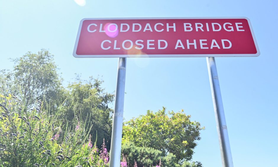 Looking up at red sign saying "Cloddach Bridge closed ahead".