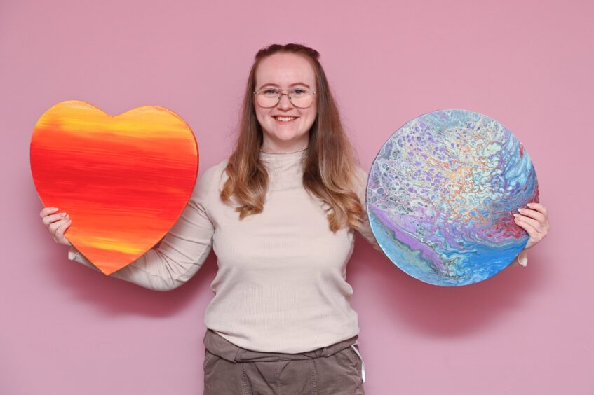 Holly Lazenby of Lazy Bean holding two canvases, one heart-shaped and one round