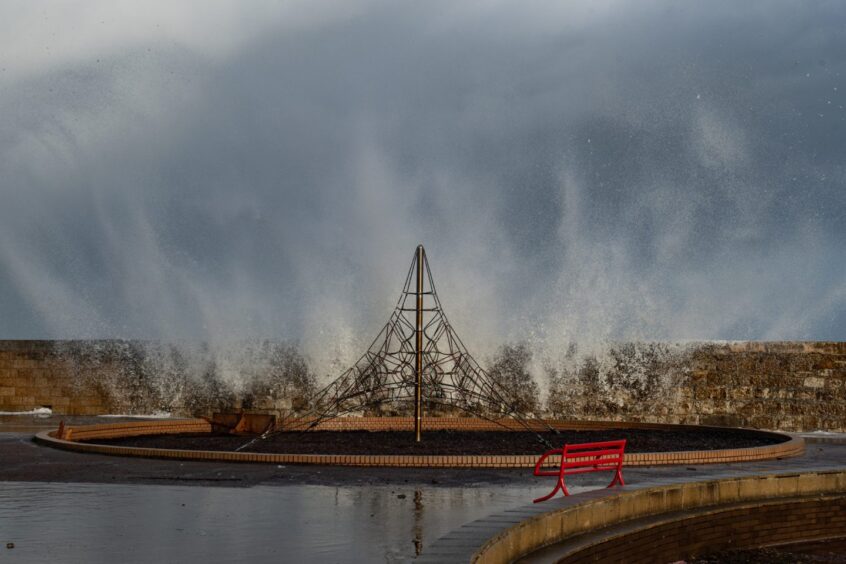 Waves splash over the harbour wall at Lossiemouth.
