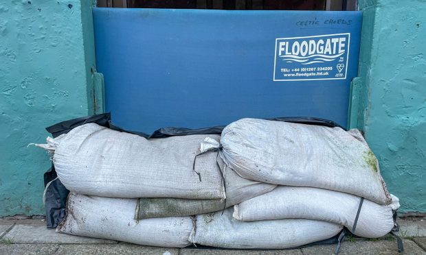 Floodgate and sandbags in front of a door.