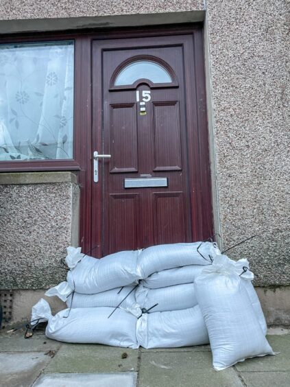 A residential property with sandbags in front of door.