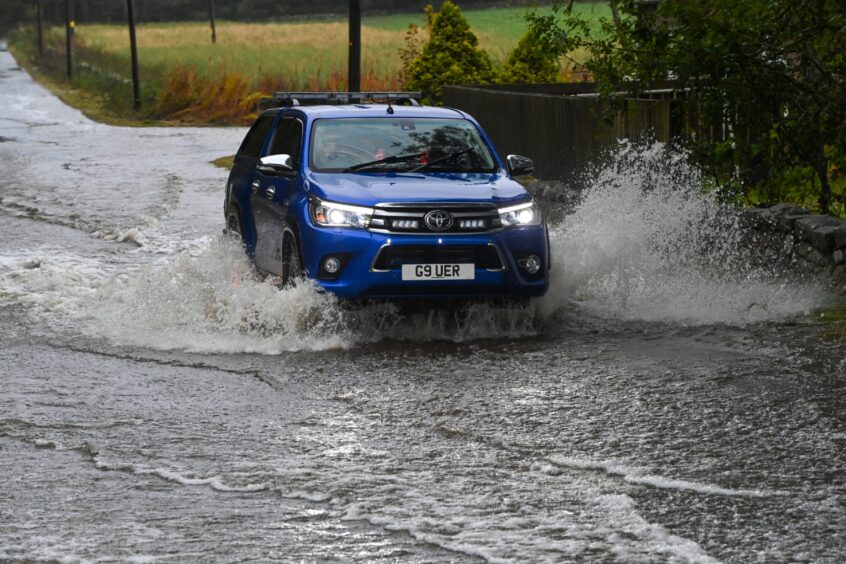 Car going through floodwater on the A944 Westhill to Dunect road during Storm Babet.