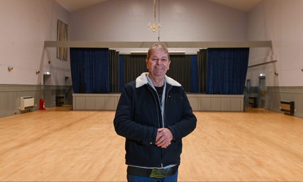 Gordon Cowie standing inside Fishermen's Hall main hall with stage behind.