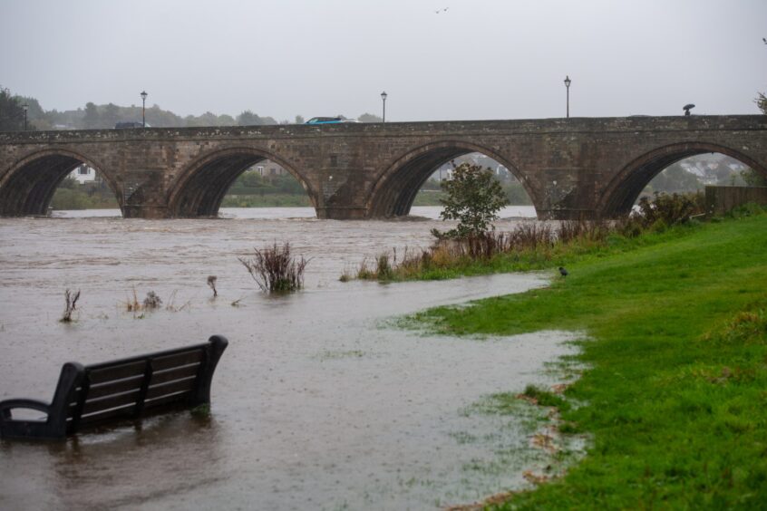 A bench is submerged in the overflow from flooding at the River Dee.