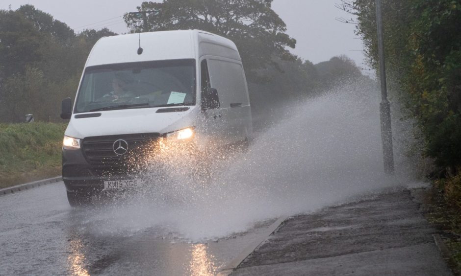 Man driving van through road at Marykirk, Aberdeenshire, which has been flooded due to Storm Babet.