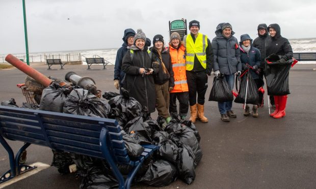 People standing behind bags of rubbish.