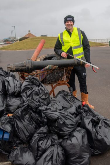 Mike Scotland standing behind bags of rubbish.