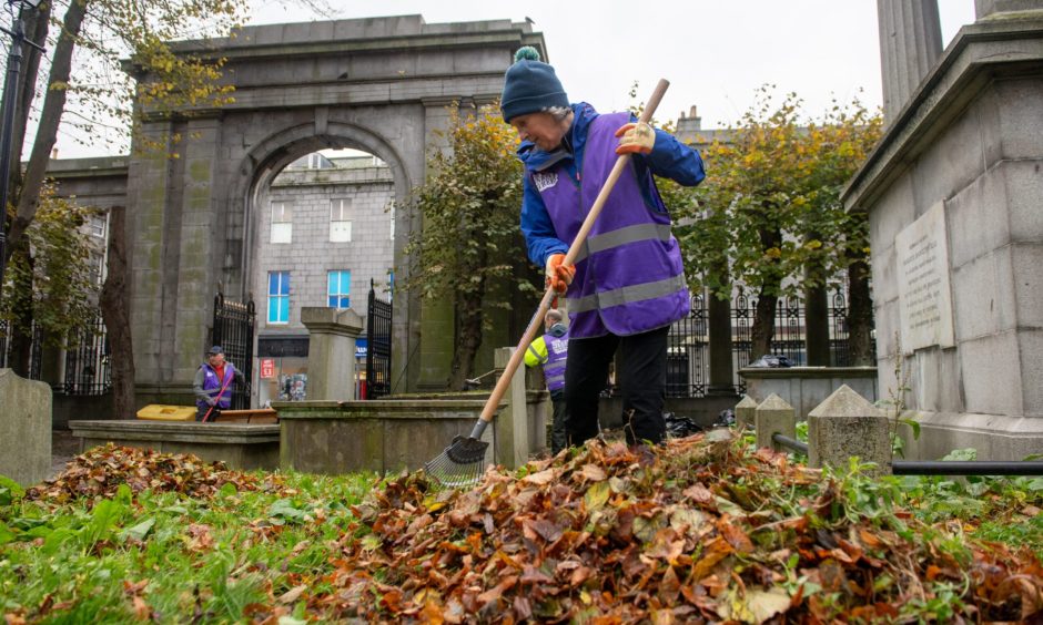 Volunteers raking leaves in St Nicholas Churchyard