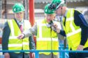 Company chairman Tom Bruce-Jones along with King Charles on a tour inside the sawmill talking with site manager Duncan Cassie. Image: Kami Thomson/DC Thomson