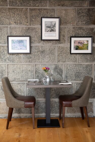 Striking granite wall within The Forbes Arms Hotel, featuring paintings from local artists.