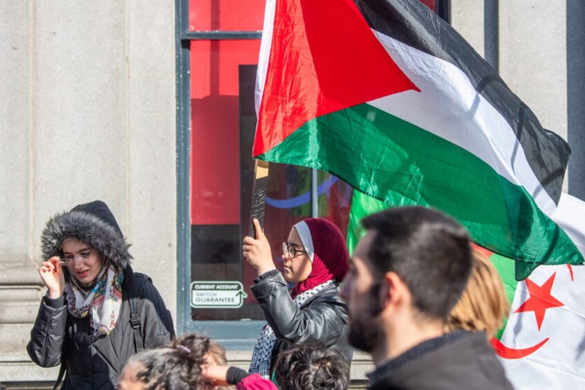 Woman holds Palestine flag at rally in Aberdeen