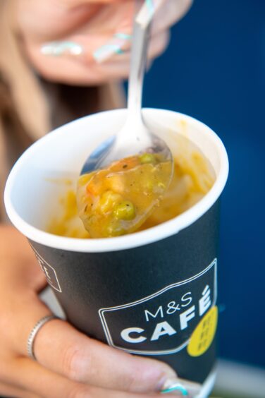 Close up of the soup in a disposable coffee cup.