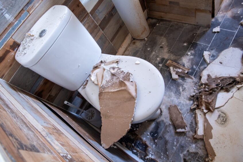 The toilet with broken plaster from the ceiling on the lid and across the floor