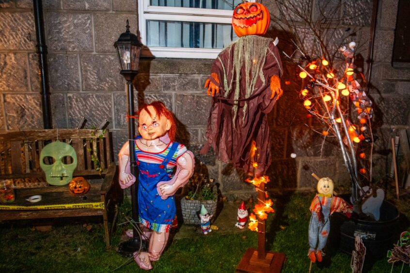 Life-size Chucky in decorated garden for Halloween.