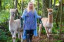 Emily Coull with two Alpacas in a forest