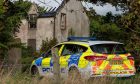 Police car sits outside the fire stricken remains of Sunbank House in Lossiemouth.