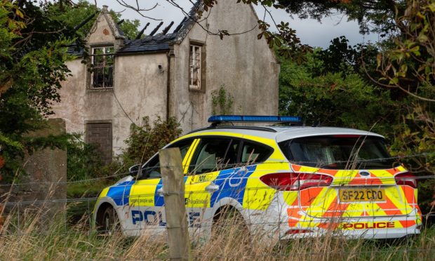 Police car sits outside the fire stricken remains of Sunbank House in Lossiemouth.