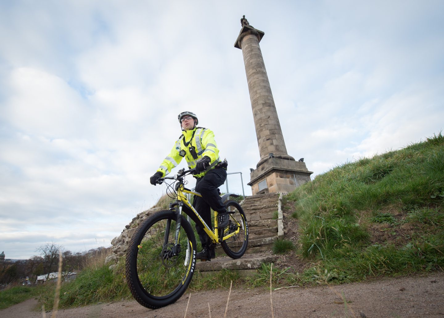 Police cyclist on Ladyhill in Elgin with monument behind. 