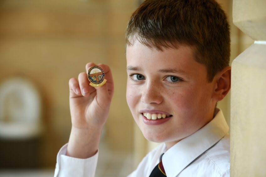Peter MacKinnon of Portree, Sky with his gold badge for solo singing fluent boys 11-12.
