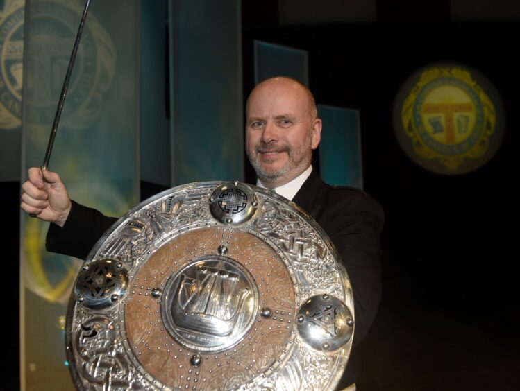 Conductor Ronald Murray holding the Lorn Shield and the Mrs C MacDonald Silver Baton.