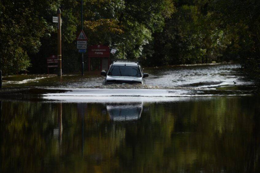 A vehicle wades through water up to its bonnet.