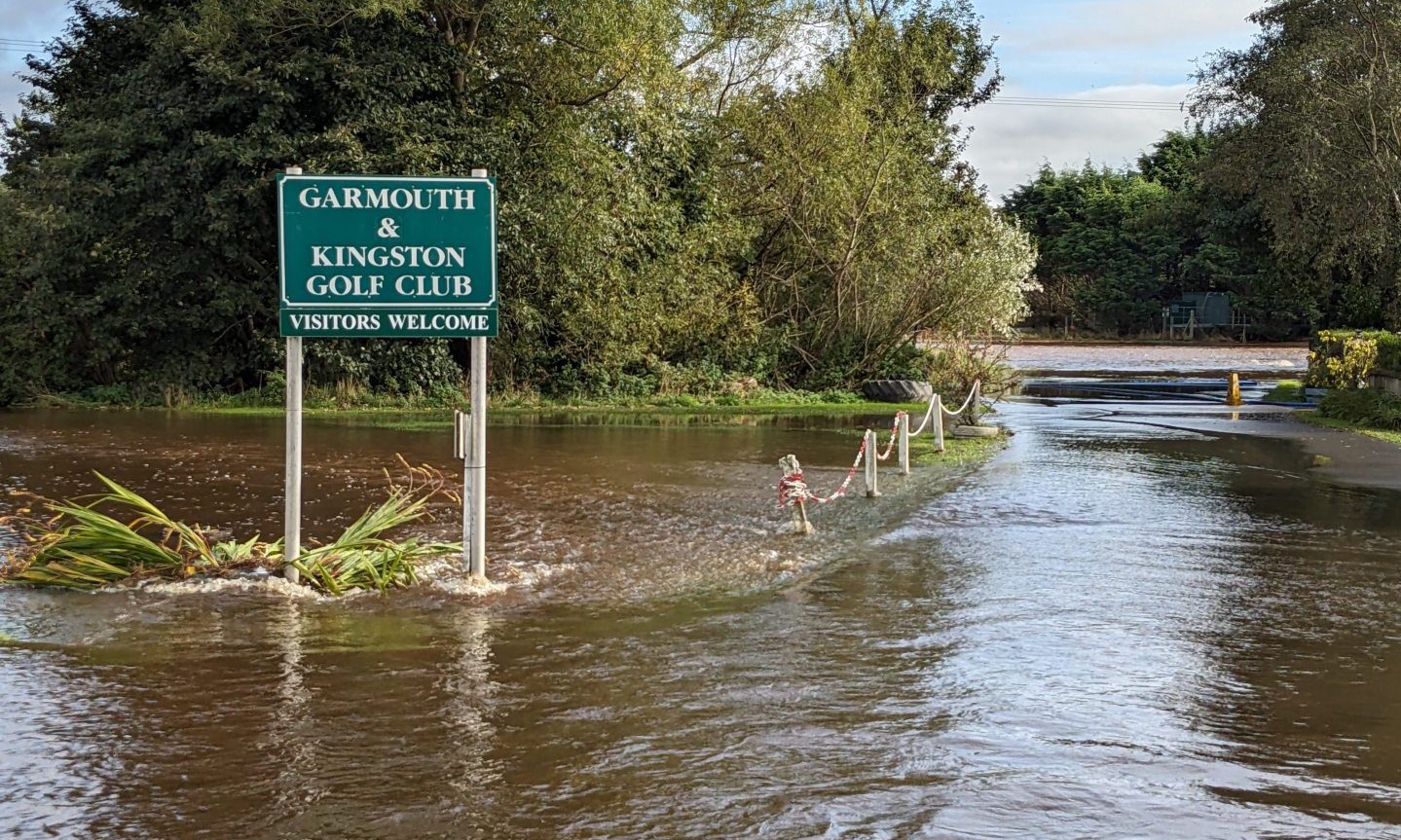 Sign for Garmouth Golf Club surrounded by flood water. 