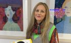 Sally Reaper, director of Look Again at Gray's School of Art smiling in front of two framed artworks.
