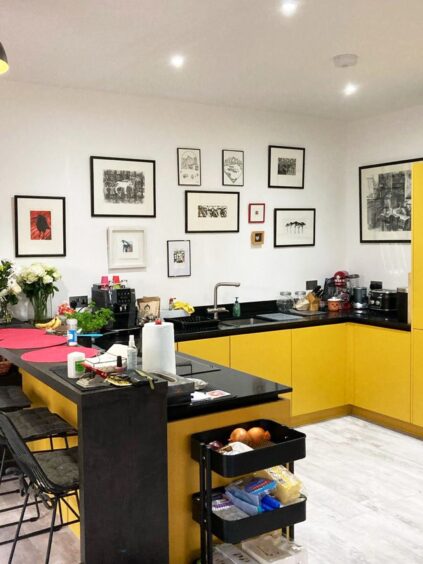 A picture gallery above the yellow and black counters in the kitchen