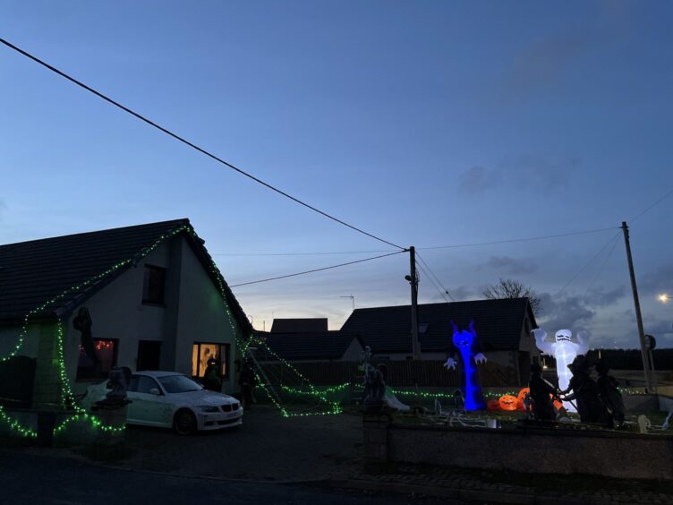 Exterior of Valleri and Craig Carle house in St Fergus, Aberdeenshire, decorated with green LED lights and spooky figures for Halloween.