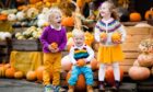 Three smiling and laughing children at a pumpkin patch.