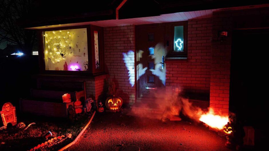 House decorated for Halloween in Aberdeen, featuring projected ghosts and jack-o-lanterns.