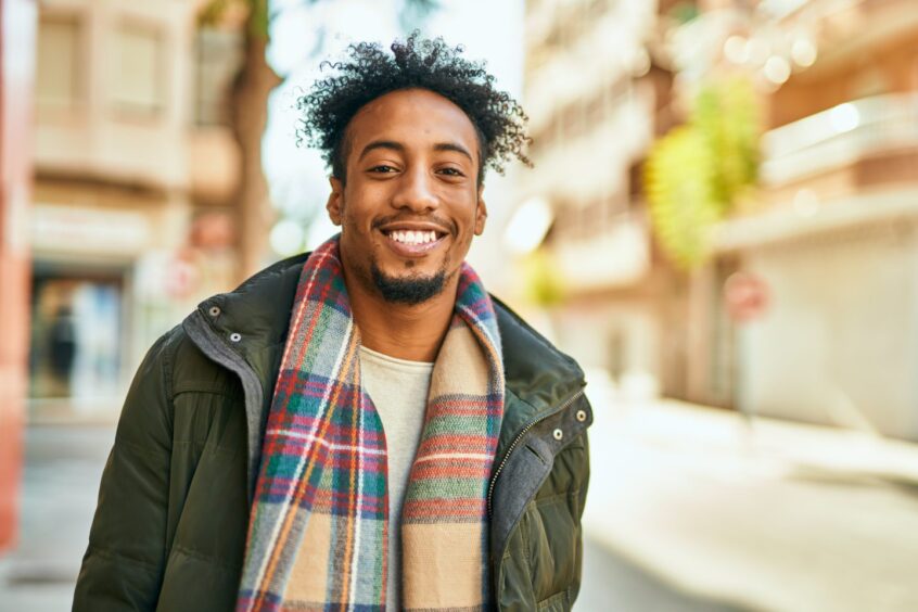 Man standing outside in winter wearing a scarf and smiling.