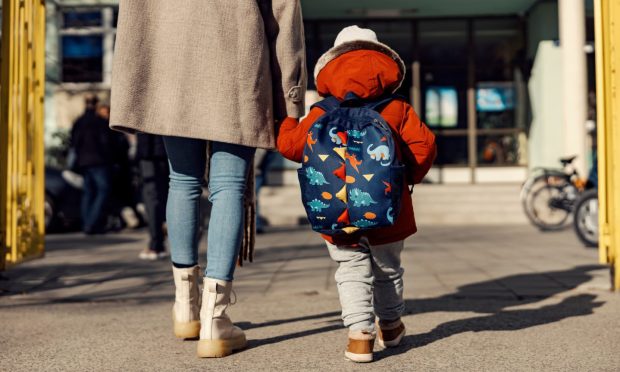 A mother entering the nursery school yard with her pre-school boy