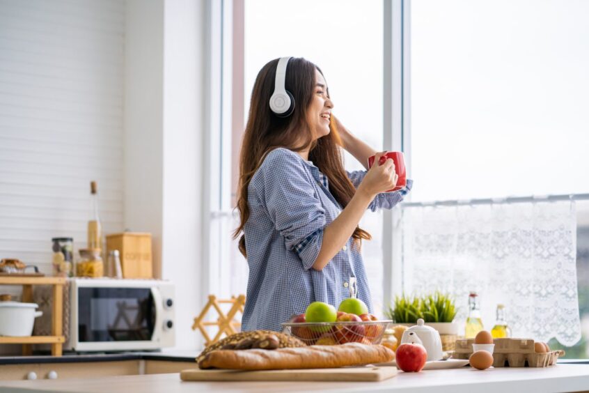 Woman in kitchen looking out of window and cooking.