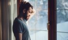 Man struggling with winter blues looking out the window.