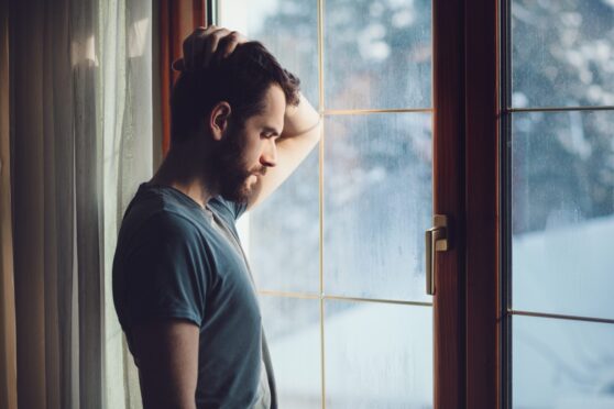 Man struggling with winter blues looking out the window.