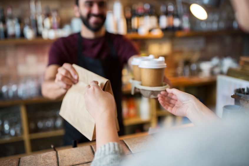 barista handing over takeout coffee to a customer