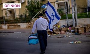 A man with an Israeli flag walks an empty street in Sderot, Israel (Image: Martin Divisek/EPA-EFE/Shutterstock)