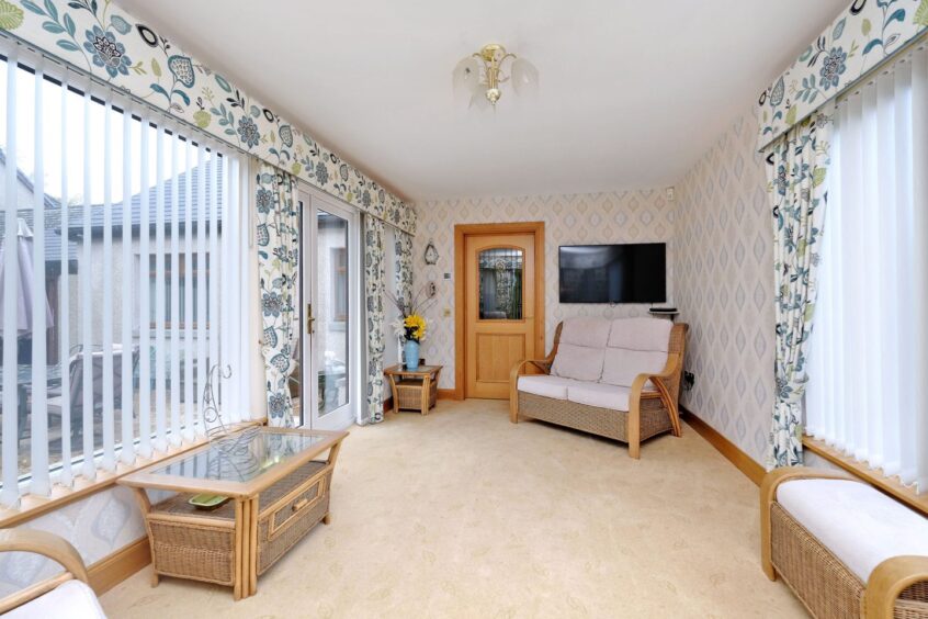 Bright sunroom in the bungalow for sale in Inverurie, featuring large windows and neutral interiors.