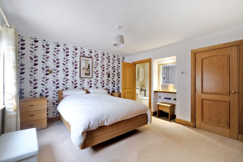 Ensuite bedroom in the Aberdeenshire property, featuring light carpets and floral wallpaper.